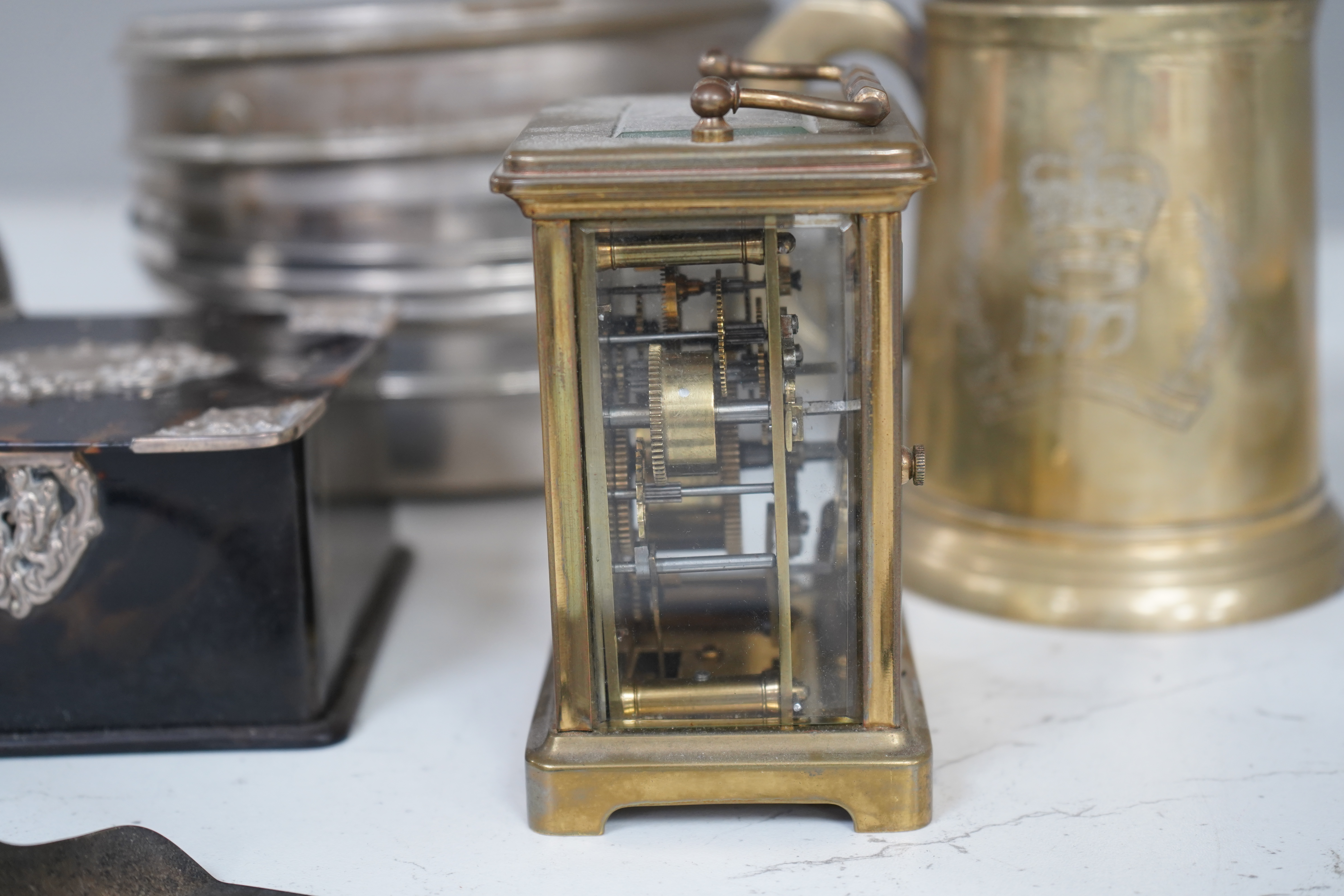 A small collection of metalware to include a white metal mounted tortoiseshell box, brass cased carriage clock with subsidiary dial and a pewter tankard. Condition - poor to fair